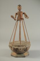 A CARVED WOOD ARTICULATED FIGURE on a base, carved with angel heads. 15.5ins high.
