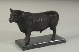 A BRONZE STANDING BULL on a black marble base. 9ins long.