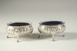 A PAIR OF GEORGE III SILVER OVAL SALT CELLARS with sapphire blue liners on four pad feet. London