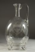 A GOOD VERY LARGE GLASS JUG engraved with a coat of arms and supported on four lion feet. 16ins