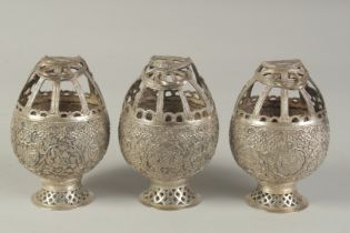 THREE KASHMIRI FINELY EMBOSSED AND CHASED WHITE METAL HANGING INCENSE BURNERS, decorated with exotic