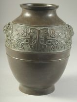 A CHINESE BRONZE VASE, with a band of archaic design and twin beast-head handles, 22cm high.