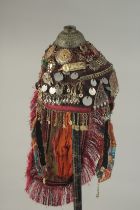 AN UZBEK EMBROIDERED CEREMONIAL HEADPIECE, adorned with niello pendants, coins and coloured glass or