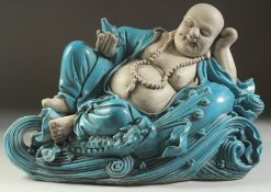 A LARGE TURQUOISE GLAZED POTTERY HAPPY BUDDHA, in reclining position with coiled dragon at his feet,