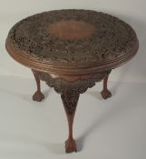 A FINE INDIAN CARVED WOOD TABLE, with intricately carved foliate border, standing on three legs