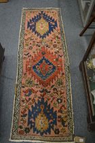 A small Persian runner or hall carpet, pink ground with stylised decoration, 176cm x 57cm.