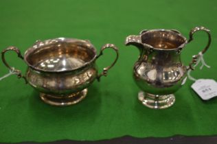 A silver cream jug and matching sugar bowl.