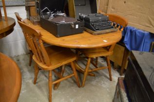 A modern pine drop leaf kitchen table with four spindle back chairs.