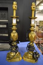 A pair of brass candlestick/table lamps together with two pairs of candlesticks.