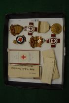 A collection of four enamel and gilt metal Red Cross nursing badges together with associated