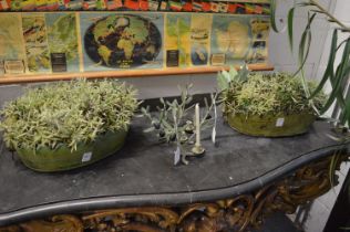 A pair of green painted Toleware troughs containing artificial shrubs together with a pair of candle