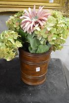 A wooden jardiniere containing artificial flowers.