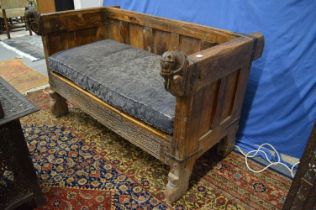 A large Eastern hardwood settee with horse head terminals to the arms.