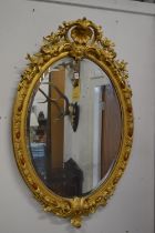 A good 19th century gilt framed oval wall mirror with shell and floral cresting.