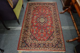 A small Persian rug, red ground with stylised floral decoration, 164cm x 100cm.