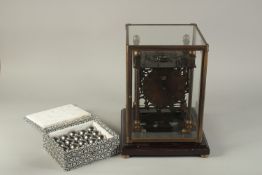 A PRESSURE BALL CLOCK, with twenty balls, in a glass case. 15ins high.