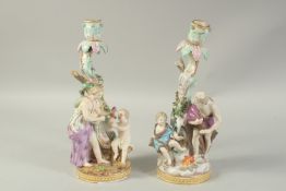 A PAIR OF MEISSEN CANDLESTICKS depicting winter and spring. 29cm high. Cross swords mark in blue.