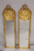 A TALL PAIR OF NARROW GILT MIRRORS with classical circular panels and garlands. 5ft 9ins high x