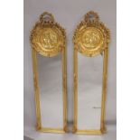 A TALL PAIR OF NARROW GILT MIRRORS with classical circular panels and garlands. 5ft 9ins high x
