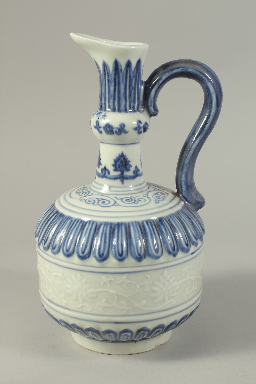 A CHINESE BLUE AND WHITE PORCELAIN EWER, with a band of carved floral decoration. 29cms high.