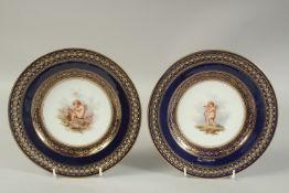 A PAIR OF MEISSEN COBALT GROUND OPEN WORK PLATES decorated with cupids, one with gilt text on