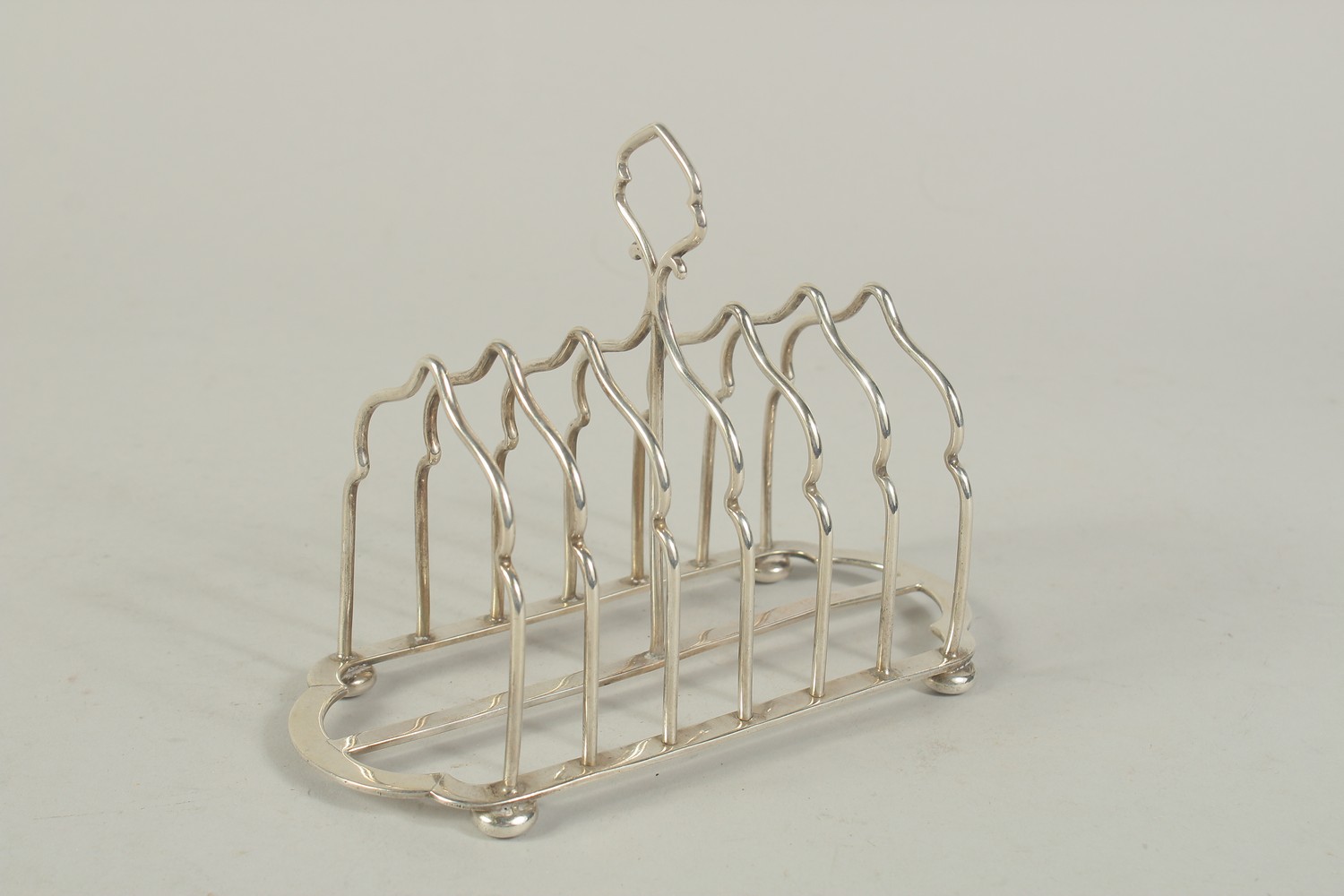 A SIX DIVISION SILVER TOAST RACK on four ball feet. London 1903. Weight: 7ozs.