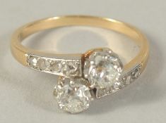 A 9CT GOLD AND DIAMOND CROSS OVER RING with diamond shoulders.