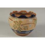 A DOULTON LAMBETH SLATERS PATENT STONEWARE CIRCULAR JARDINIERE with blue rim and leaf decoration.