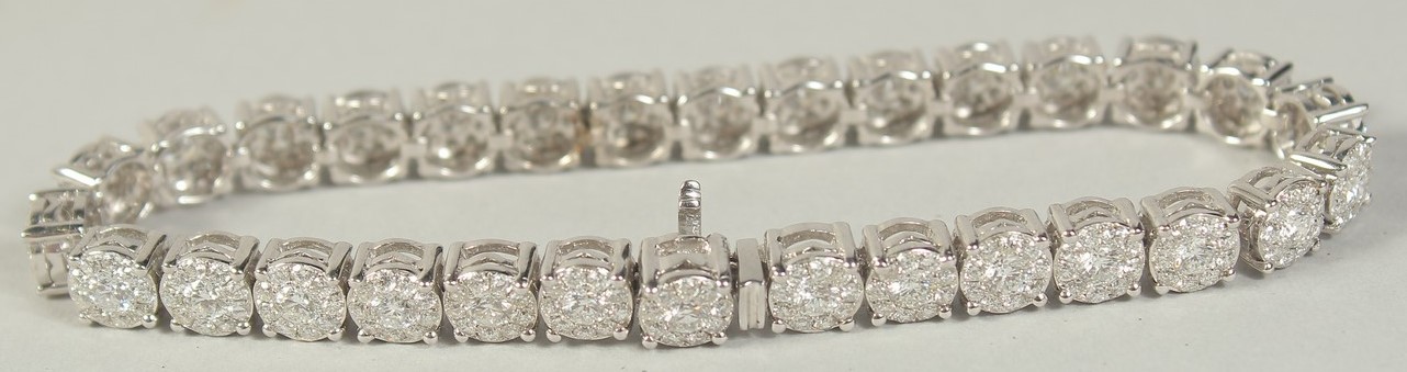 A SUPERB 18 CARAT WHITE GOLD ILLUSION SET DIAMOND LINE BRACELET with 30 cluster set diamonds. 20cm