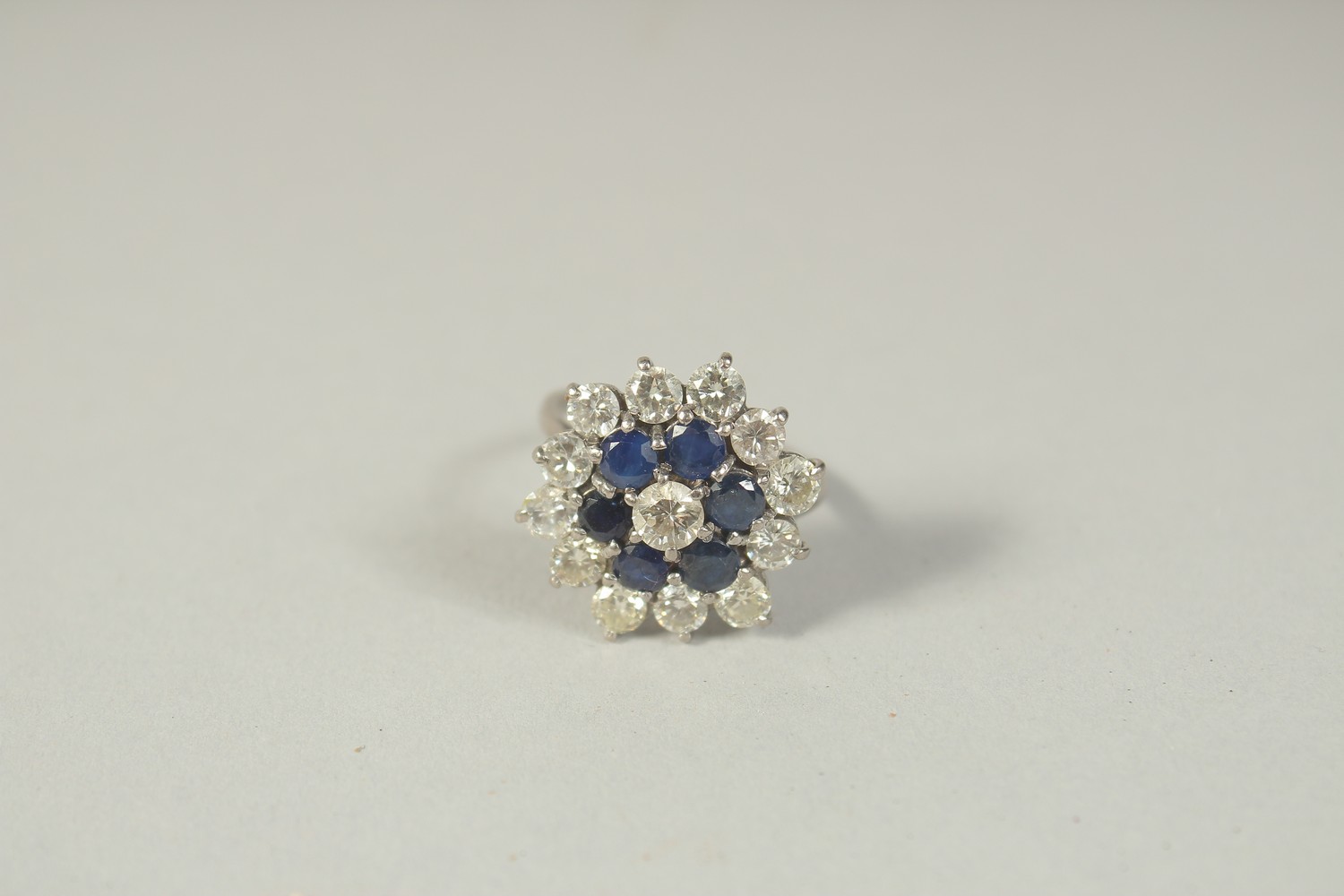 AN 18 CT WHITE GOLD DIAMOND AND SAPPHIRE CLUSTER RING.