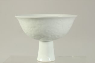 A CHINESE WHITE PORCELAIN STEM CUP with relief decoration. 5.5ins diameter.