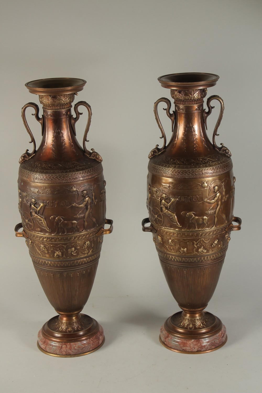 A SUPERB PAIR OF TWO-HANDLED CLASSICAL BRONZE URNS decorated with panels of classical figures.
