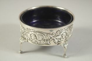 A GOOD LARGE SILVER CIRCULAR SALT with sapphire blue liner repousse side with cupids, supported on