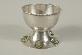 AN ARTS AND CRAFTS SILVER CIRCULAR SALT with bead edges, the base set with five stones. 2.25ins