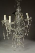 A CUT GLASS CHANDELIER with six scrolling branches and prism drops.