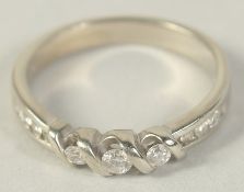 AN 18CT GOLD DIAMOND THREE STONE RING with diamond shoulders.