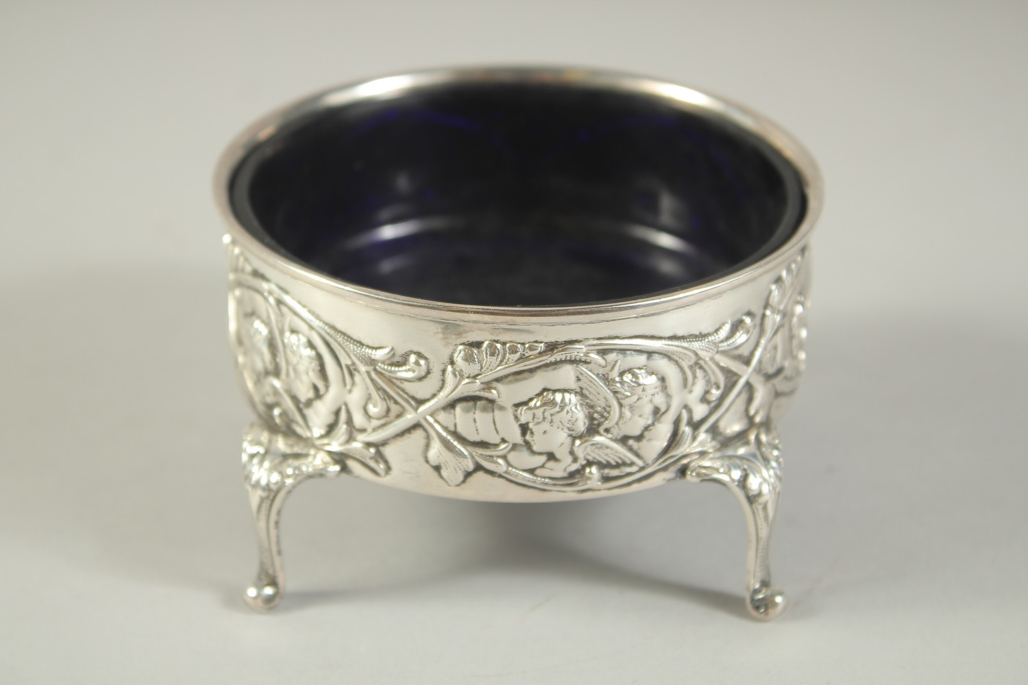 A GOOD LARGE SILVER CIRCULAR SALT with sapphire blue liner repousse side with cupids, supported on - Bild 2 aus 6
