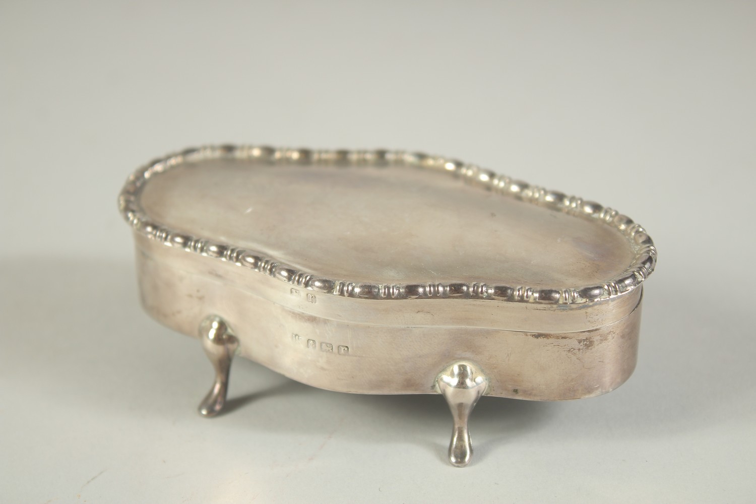 AN OVAL SILVER JEWELLERY BOX with velvet interior on four pad feet. 4ins long. Birmingham 1916.