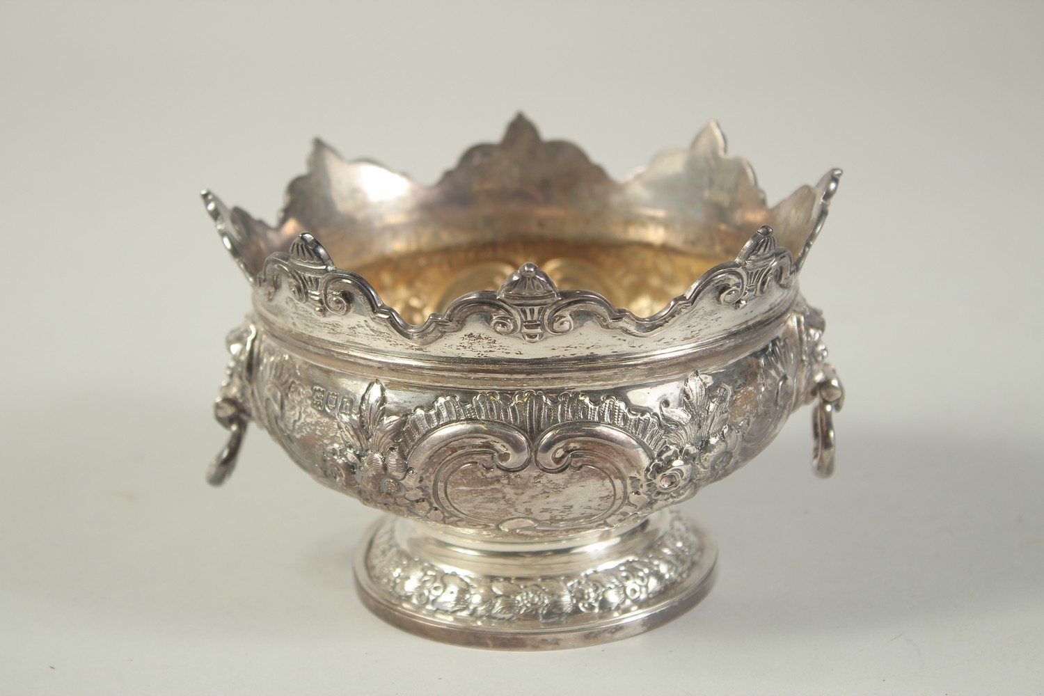 A GOOD SMALL SILVER MONTEITH BOX with repousse decoration and lion ring handles. 5.25ins diameter.