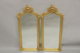 A SMALL PAIR OF GILTWOOD NARROW MIRRORS with scroll tops. 3ft 9ins high x 1ft 2ins wide.