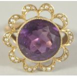 A PURPLE STONE AND SEED PEARL RING. Size M.