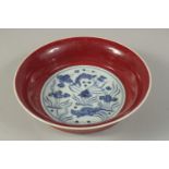 A CHINESE COPPER RED AND BLUE & WHITE BOWL, the interior painted with fish and algae. 22cms