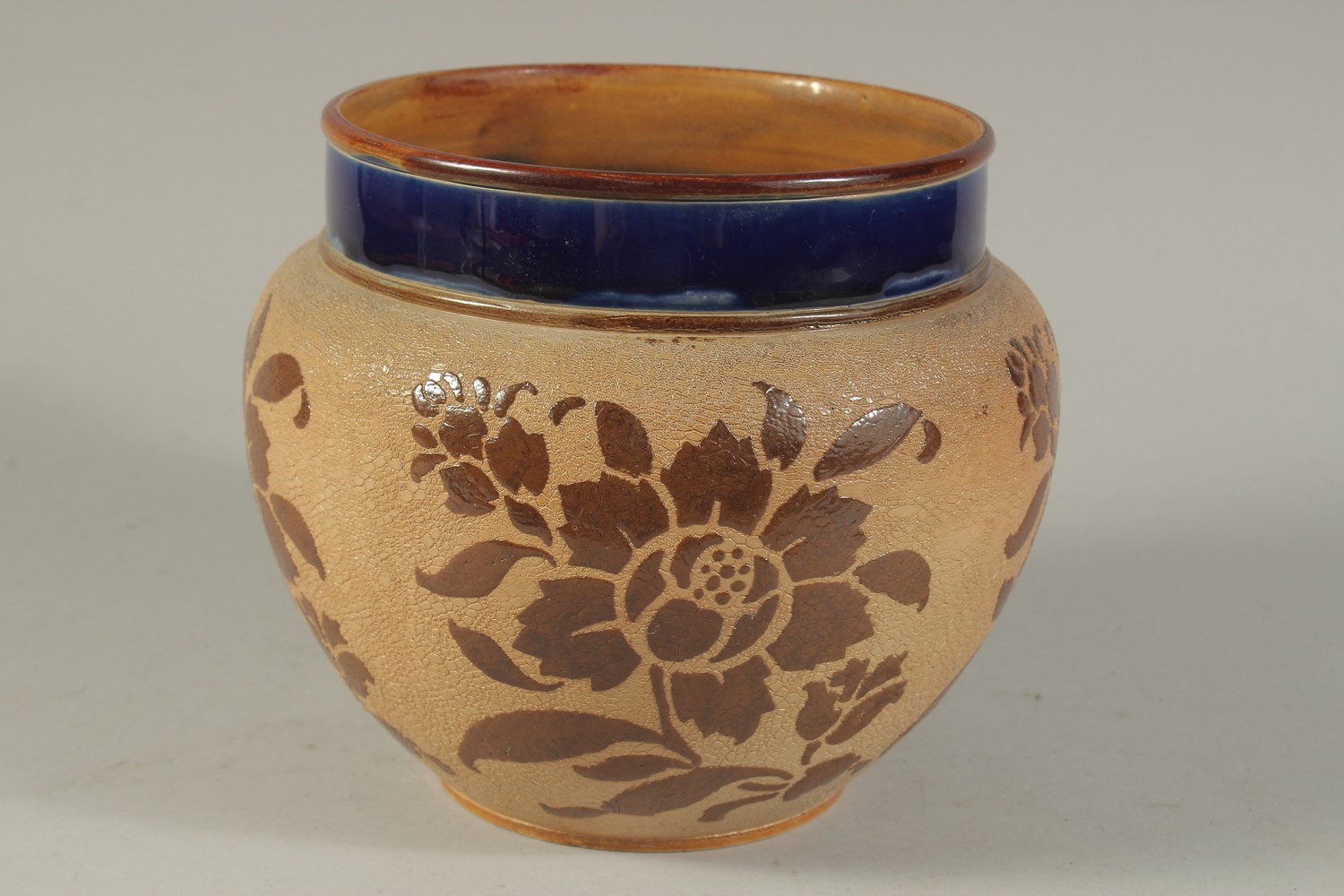 A ROYAL DOULTON SLATERS PATENT STONEWARE CIRCULAR JARDINIERE with blue rim, the body with leaves.