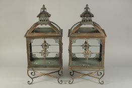 A PAIR OF RECTANGULAR COPPER LANTERNS on curving legs. 21ins high.