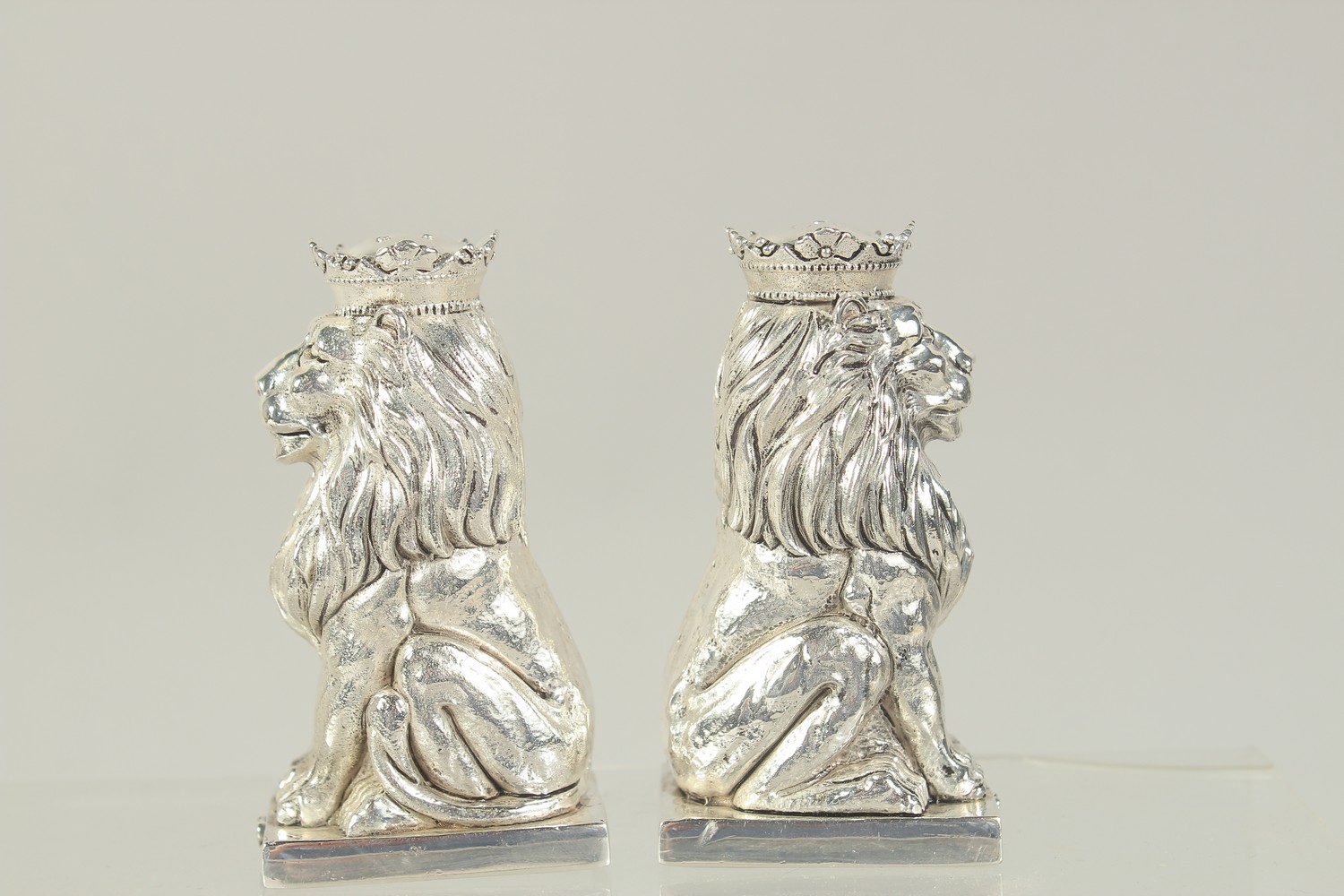 A PAIR OF SILVER PLATED ROYAL LIONS SALT AND PEPPERS. 3.25