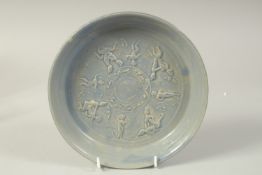 A CHINESE BLUE GLAZE POTTERY DISH, with carved erotic figures, 21cm diameter.