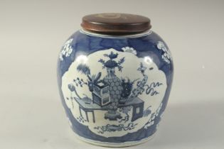 AN EARLY 20TH CENTURY CHINESE BLUE AND WHITE PORCELAIN JAR AND HARDWOOD COVER, decorated with panels