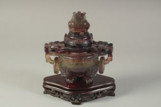 A CHINESE CARVED AMETHYST TRIPOD KORO AND COVER, on a hardwood stand, with twin drop-ring handles