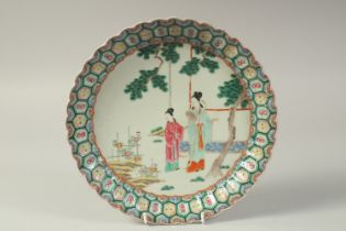 A CHINESE FAMILLE ROSE PORCELAIN PLATE, painted with female figures in a garden, the base with