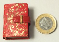 A RARE EARLY-MID 20TH CENTURY MINIATURE LEATHER BOUNDED QURAN, 3.8cm x 2.8cm.
